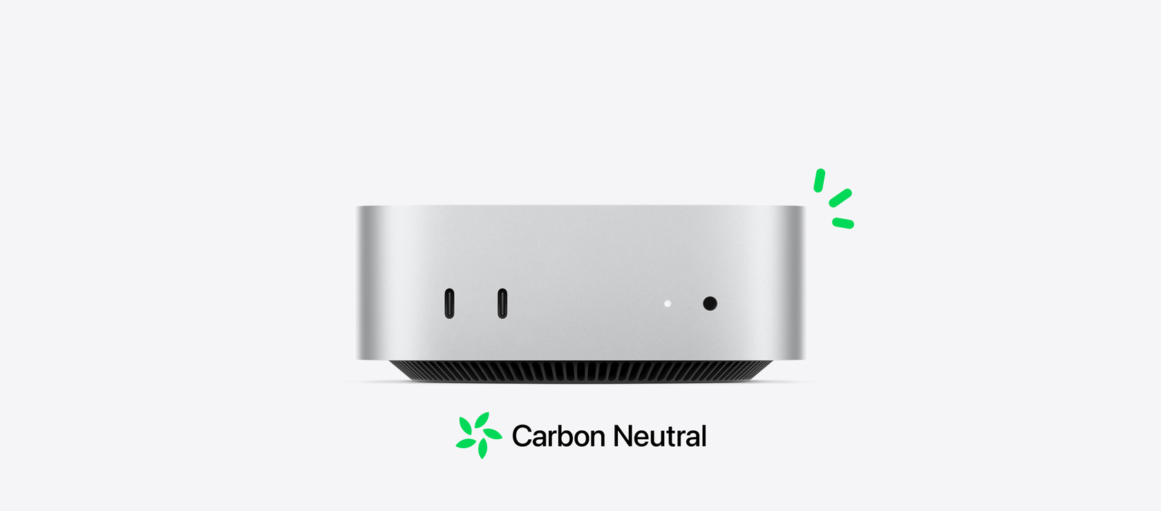 银色 Mac mini 的正面视图，展示正面的各个端口，另有绿色小标志表明设备的碳中和特性。